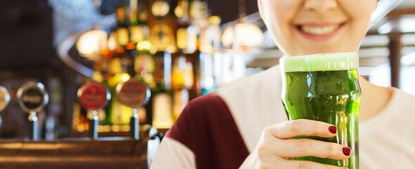 alcohol drinks and st patrick's day concept - close up of woman with green beer in glass over bar background