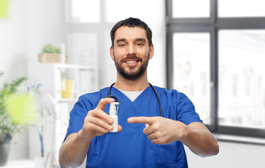 Fototapeta premium healthcare, profession and medicine concept - happy smiling doctor or male nurse in blue uniform with oral spray and stethoscope over medical office at hospital background