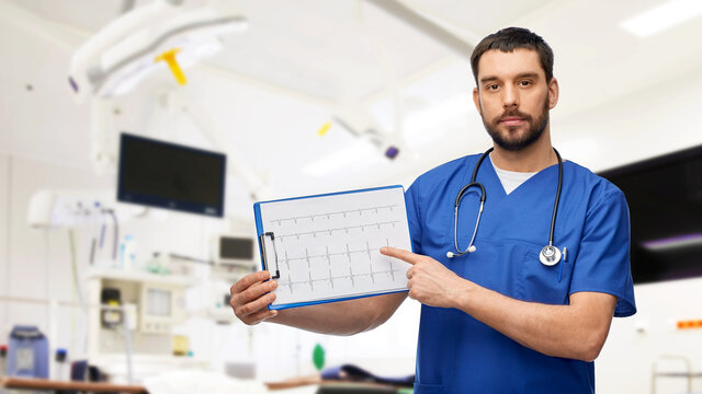medicine, healthcare and surgery concept - doctor or male nurse in blue uniform with cardiogram on clipboard over operating room at hospital background