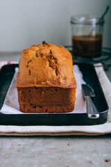 Cake with dried prunes and salted caramel on a black metal tray on gray background