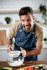 Happy man baking in the kitchen. Man making delicious food at home.
