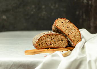 Black sliced bread on a wooden board with a knife against a white background. Blurred background. Copy space