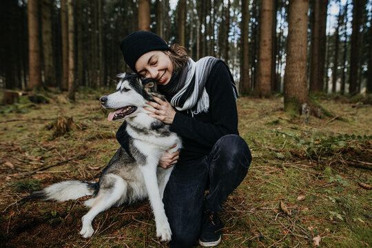 Junge Frau und ihr Hund kuscheln im Wald 