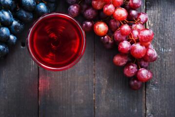 glass of red wine and grapes on black wooden table background