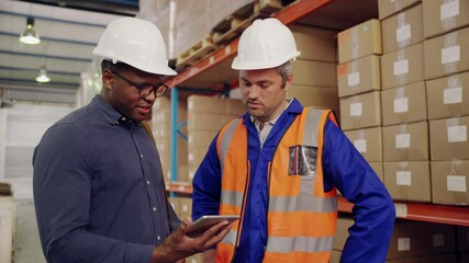 Smiling caucasian male warehouse worker and african manager looking at digital tablet discussing in storage factory - Powered by Adobe
