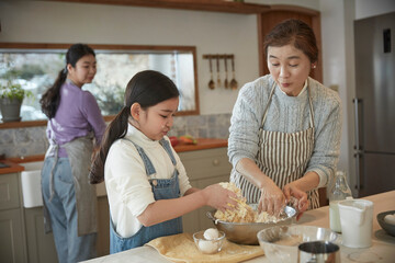 Happy adorable little child girl in apron enjoying cooking homemade pastry together with family at home.