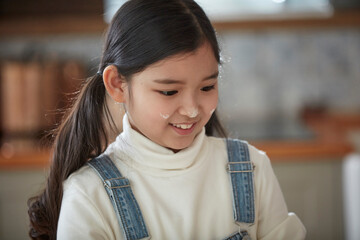 Happy adorable little child girl in apron enjoying cooking homemade