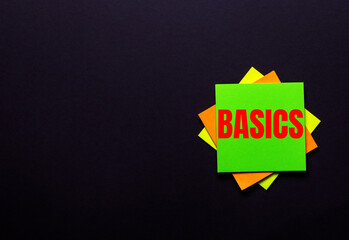 The word BASICS on a bright sticker on a dark background. Copy space
