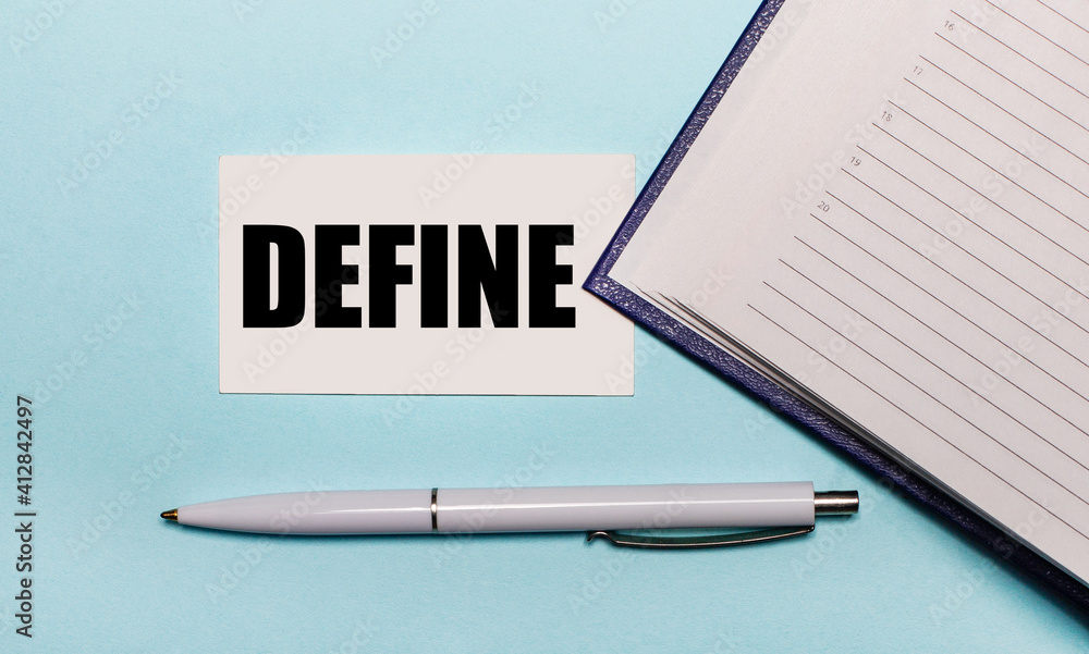 Poster on a light blue background, an open notebook, a white pen and a card with the text define. view from