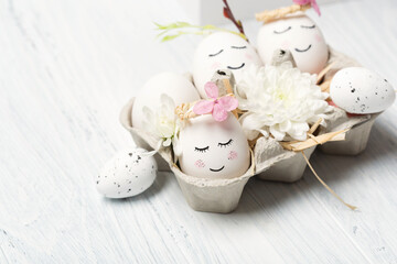 Zero waste Easter concept with white cute eggs, green tree branches, quail feathers and spring flowers on white wooden background.