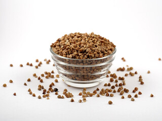 Bowl with raw uncooked buckwheat on white background. Top view. The texture of dry buckwheat. Scattered buckwheat.