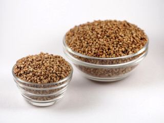 Two bowls with raw uncooked buckwheat on white background. Top view. The texture of dry buckwheat.