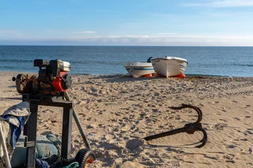 Crédence de cuisine en verre imprimé Plage de Bolonia, Tarifa, Espagne small motor winch and anchors and small wooden fishing rowboats on a sandy beach