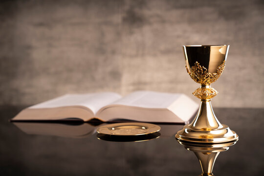 Catholic symbols composition. Religion concept. The Cross, monstrance,  Holy Bible and golden chalice gray background. 