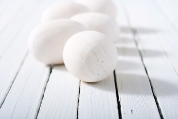 white painted wooden eggs on bright wood table background