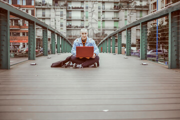 A girl with her laptop sitting on the bridge