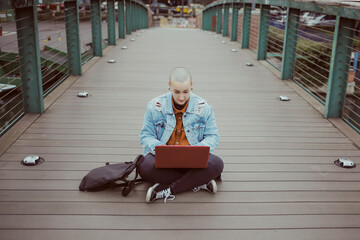 A girl with her laptop sitting on the bridge