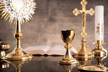 Fototapeta na wymiar Catholic symbols composition. Religion concept. The Cross, monstrance, Holy Bible and golden chalice gray background. 