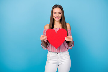 Portrait of lovely lovable cheerful straight-haired girl holding in hands red heart isolated over bright blue color background