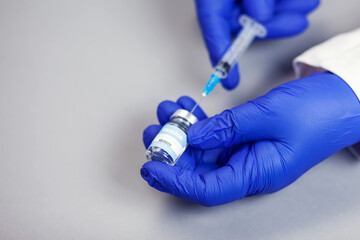 Bottle with vaccine against covid 19 and syringe in hand of researcher wearing gloves. Vial with coronavirus vaccine developed for protection against COVID-19. Healthcare and medical concept.