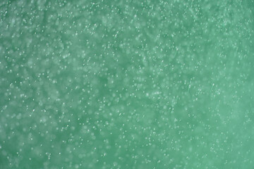 Abstract festive background with selective focus. Bright particles on green background. Splashes, space energy flow