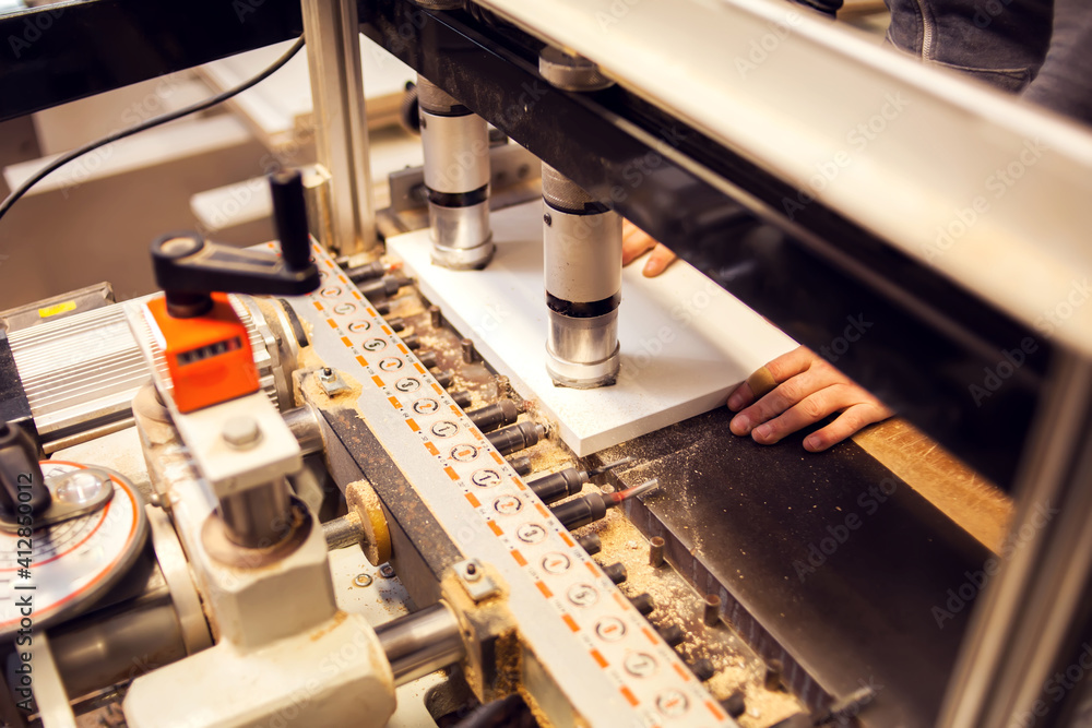 Wall mural A drilling machine makes a hole in a wooden slab. Production and manufacture of wooden furniture in furniture factory.