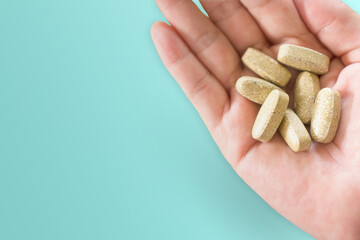 Top view of alternative organic medicine or herbal viatmin supplement capsule tablet on woman hand with copyspace background. Concept of healthy eating.