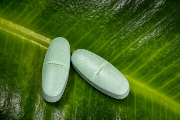 Herbal medicine pills on green leaf