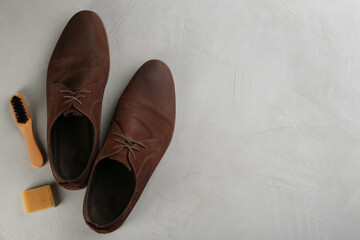 Stylish footwear with shoe care accessories on light grey stone table, flat lay. Space for text