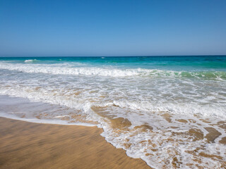 Fototapeta na wymiar Fuerteventura, Spain - Atlantic ocean coast at Canary Islands with beautiful turquoise water. Hot sunny beach day. 