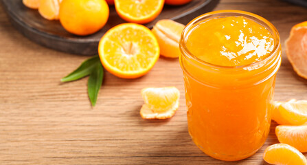 Delicious tangerine jam on wooden table. Space for text