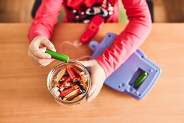 Little girl putting used batteries into jar for recycling. Child separating waste. Batteries only...