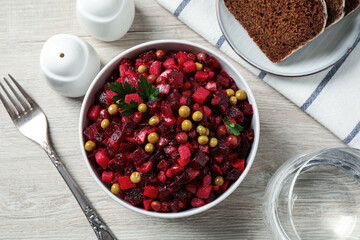 Traditional Russian salad vinaigrette served on white wooden table, flat lay