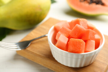 Fresh diced papaya in bowl on white table, closeup