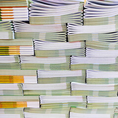 Lot of books stacked in layers in huge endless wall of knowledge. Industrial printing house. Book spines folded into stacks before trimming. Library background, typography, bookstore. Front view