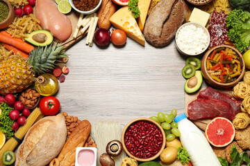 Frame made of different food products on wooden table, flat lay with space for text. Healthy balanced diet