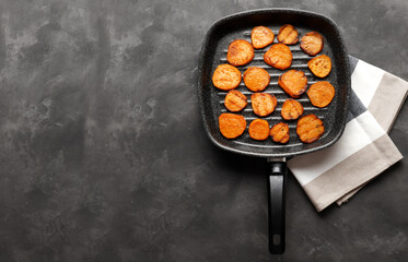Delicious grilled sweet potatoes in a frying pan on a texture table