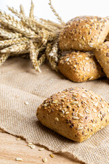 Rye bread. Bakery with crusty loaves and crumbs. Fresh loaf of rustic traditional bread with wheat grain ear or rye spike plant on natural cotton background. Healthy Food concept.