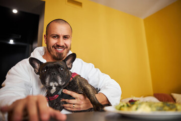 Cheerful man and his French bulldog posing for the camera