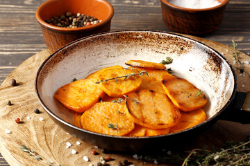 Frying pan with sweet fries on wooden table
