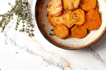 Frying pan with sweet potatoes, rosemary on a marble table