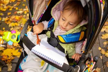 little cute toddler draws and sits in a stroller