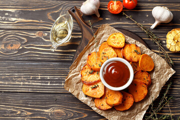Plank with delicious cooked sweet potatoes, lemon, thyme, garlic, and sauce on a rustic table