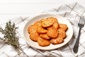 Plate with deliciously cooked sweet potatoes, rosemary, sauce and spices, herbs on a wooden table