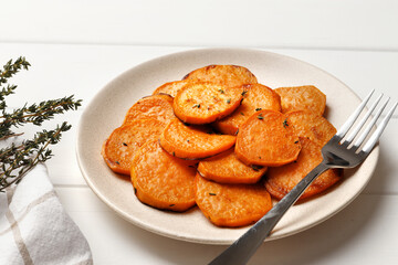 Plate with deliciously cooked sweet potatoes, rosemary, sauce and spices, herbs on a wooden table