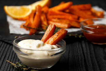 Slate plate with deliciously cooked sweet potatoes, rosemary, sauce and spices, herbs on a wooden table