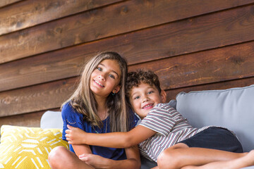 Big sister and her little brother hugging and laughing.