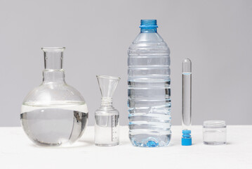 A clean water in various flasks and bottle on the gray background.