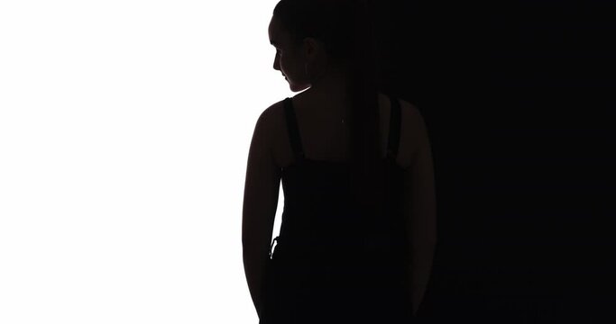 Female silhouette. Body shaming. Weight loss. Self acceptance. Dark contrast back view outline of elegant low key shy curvy woman turning head isolated on white black copy space background.