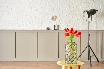Red tulip in vase at the room, decorative interior wall background style.